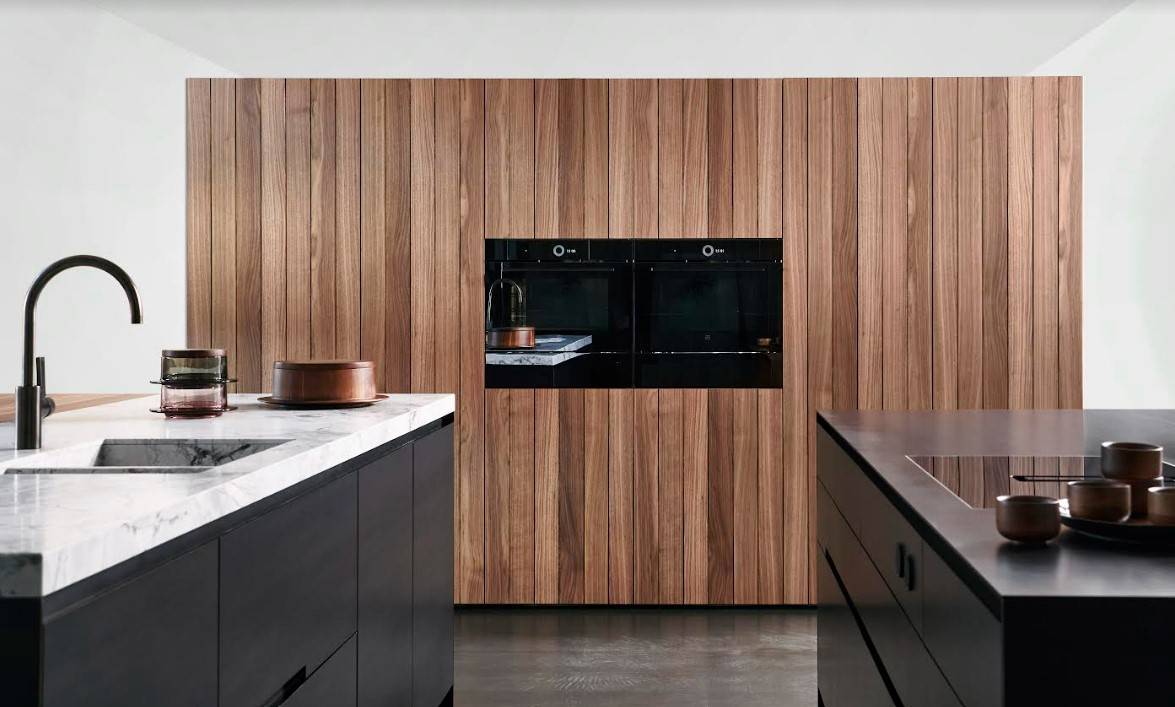 Cuisine Eggersmann haut de gamme mêlant façades en bois naturel, îlot noir élégant et plan de travail en marbre. Un design minimaliste et luxueux pour espaces contemporains.