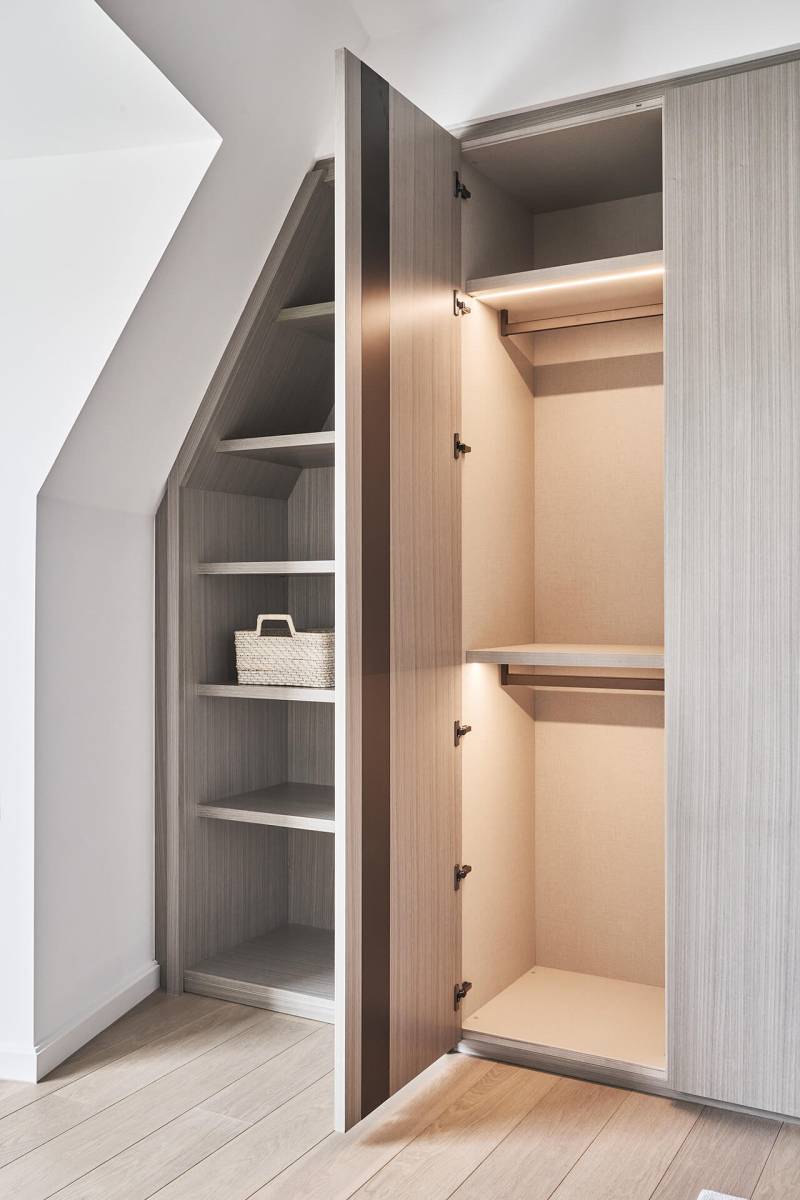 Intérieur du dressing LEMA à Bordeaux, penderie ouverte avec éclairage intégré et finitions en bois clair.