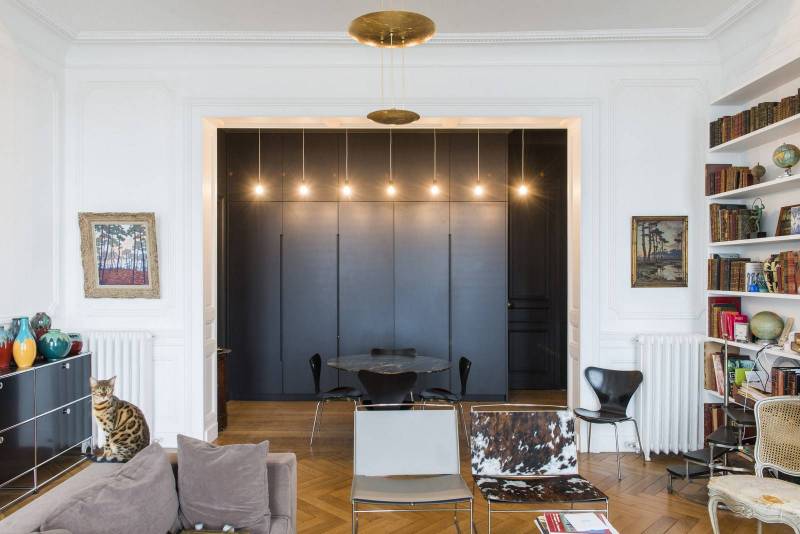 Façades en laque mate noire sans poignées, la cuisine s’efface discrètement grâce à un ingénieux système de portes rentrantes (armoire pocket)